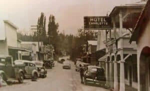 Black-and-white photo of a historic street scene featuring vintage cars and a hotel sign.