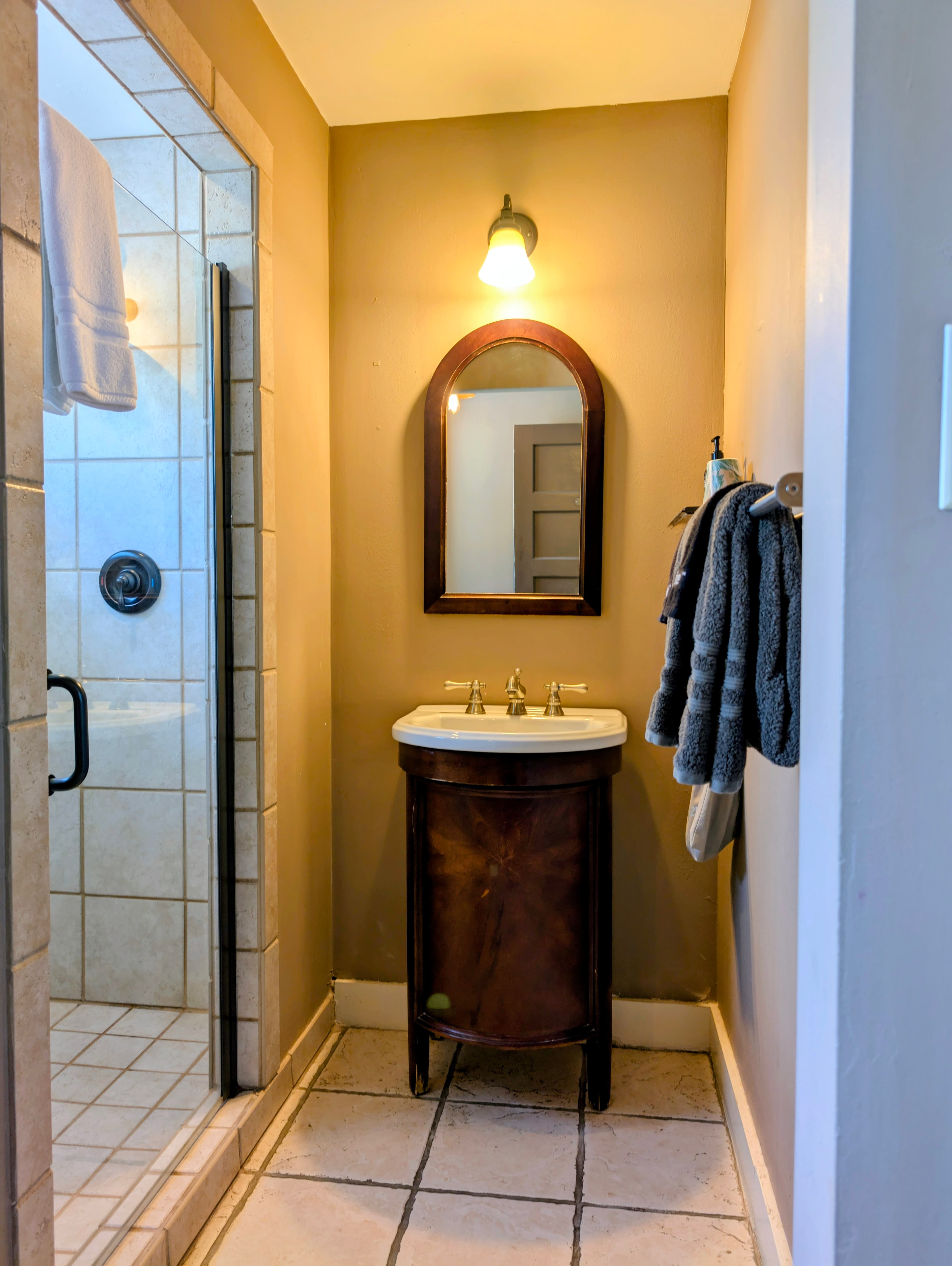 A small bathroom featuring a vintage sink, mirror, and a walk-in shower.