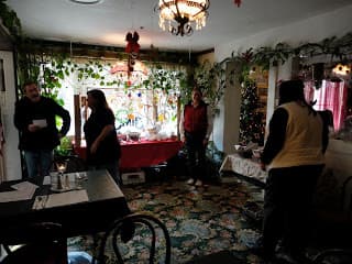 A group of four people is socializing in a cozy, decorated room with greenery and festive touches.
