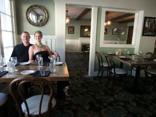 A couple sits at a wooden table in a cozy restaurant setting.