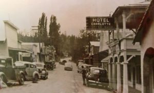 sepia tone view of road with cars in front of Hotel Charlotte around 1940.