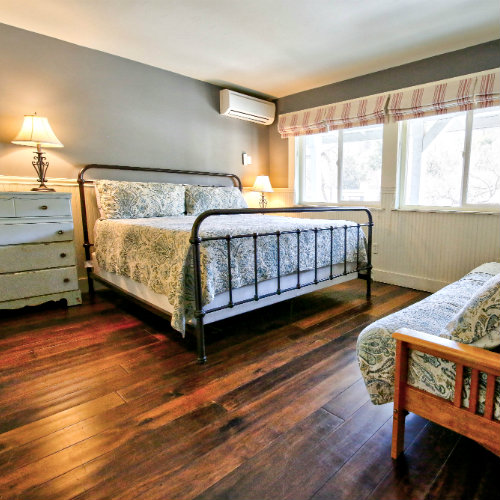 Hardwood guest bedroom with grey walls, green paisley bedding, and a futon