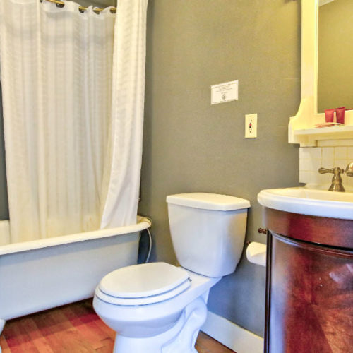 Soft green bathroom with white commode and stand up enclosed shower.